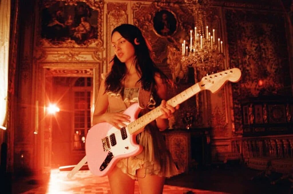 Mujer con guitarra rosa en un entorno elegante y iluminado, simbolizando el empoderamiento femenino en la música.