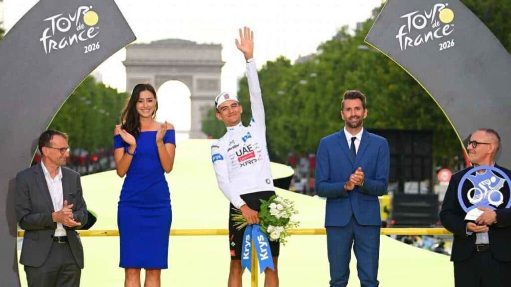 Isaac del Toro en el podio del Tour de Francia 2026, celebrando su tercer lugar junto a presentadores y el Arco del Triunfo de fondo.
