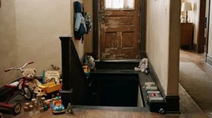 Escalera de una guardería con juguetes esparcidos y un acceso al sótano donde se encontraron a 12 niños hacinados.