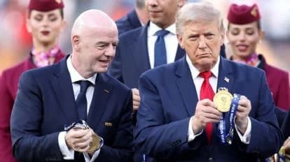 Gianni Infantino y Donald Trump sostienen medallas durante un evento, rodeados de personas con trajes formales, simbolizando