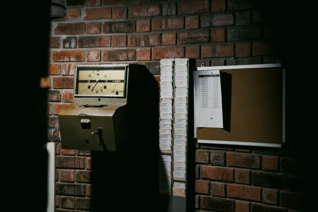 Reloj checador y tablón de anuncios en una pared de ladrillo, simbolizando el contexto laboral en México.