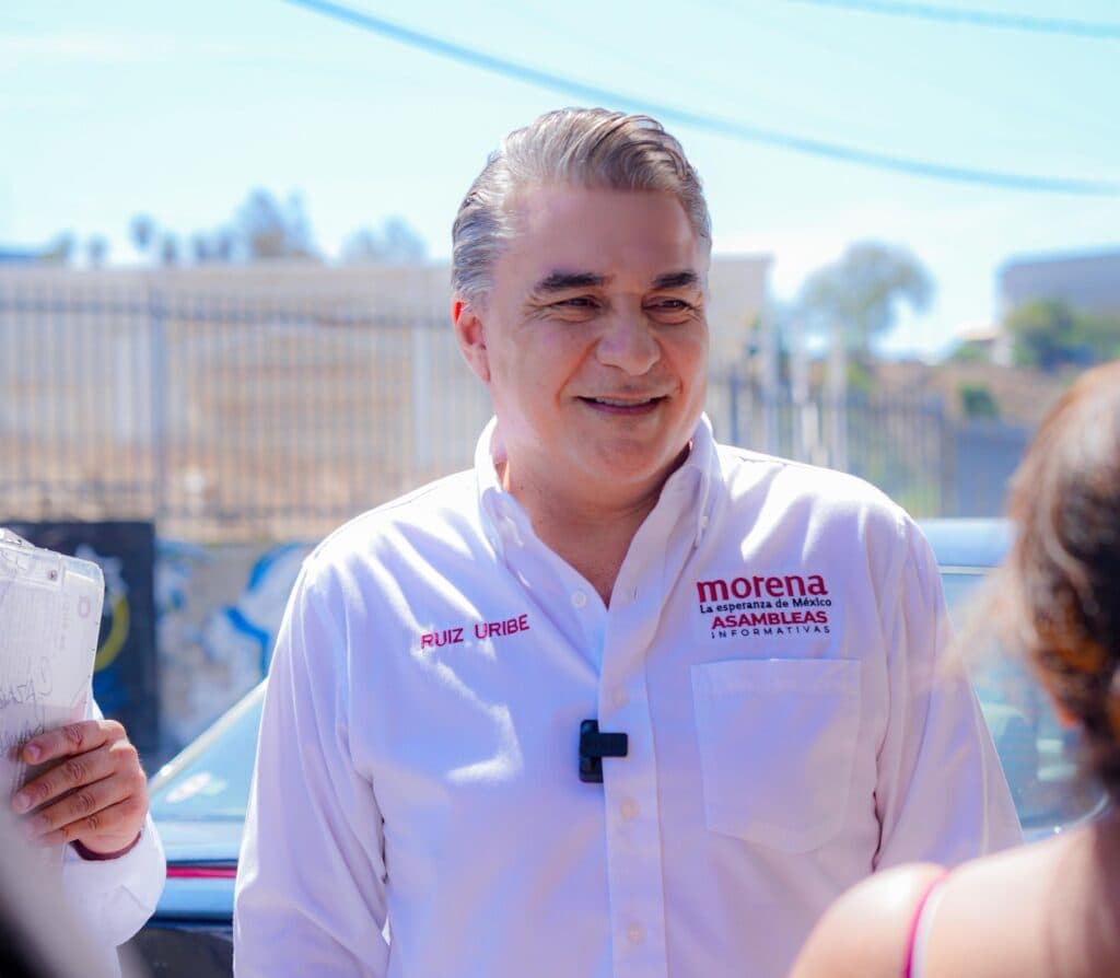 Ruiz Uribe sonríe mientras interactúa con vecinos de Lomas Taurinas, promoviendo los resultados de Claudia Sheinbaum en Tijuana.